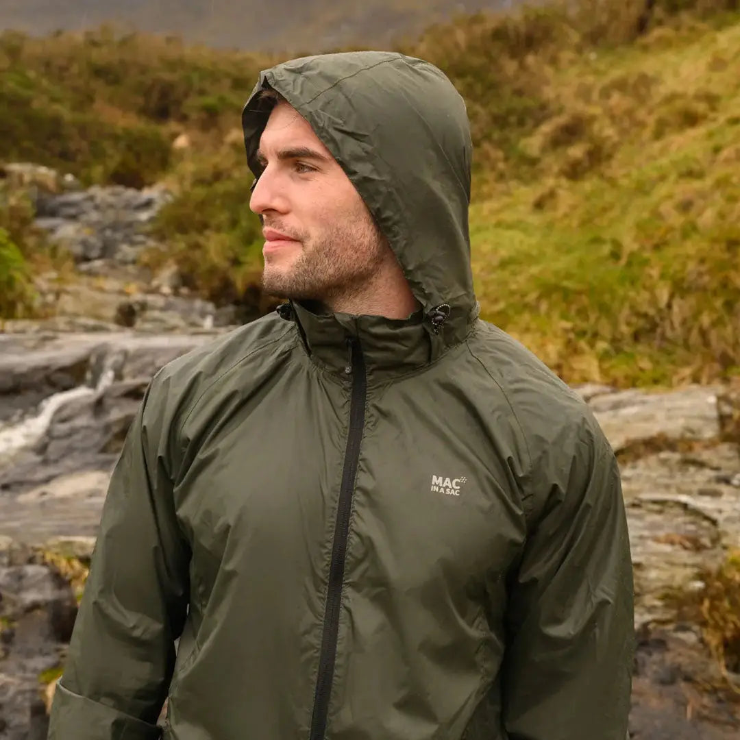 Olive green Mac in a Sac Origin 2 waterproof jacket worn outdoors by an adult