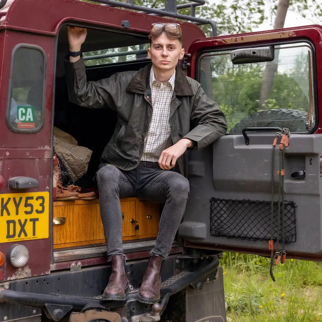 Red vintage Land Rover with open door showcasing Mens Classic Antique Wax Jacket