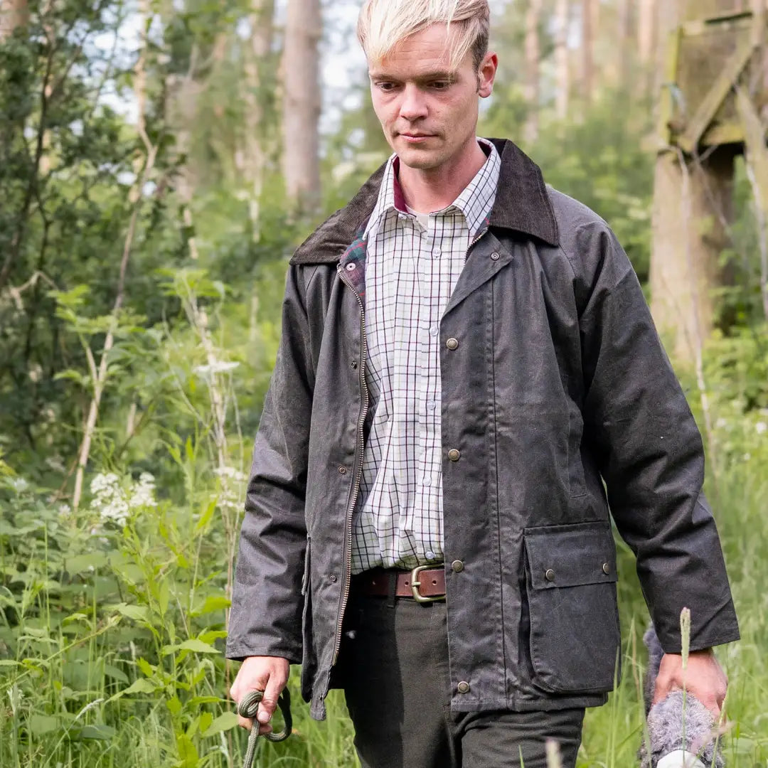 Man with blonde hair in a dark jacket and plaid shirt enjoying the outdoors in a Mens Classic Antique Wax Jacket