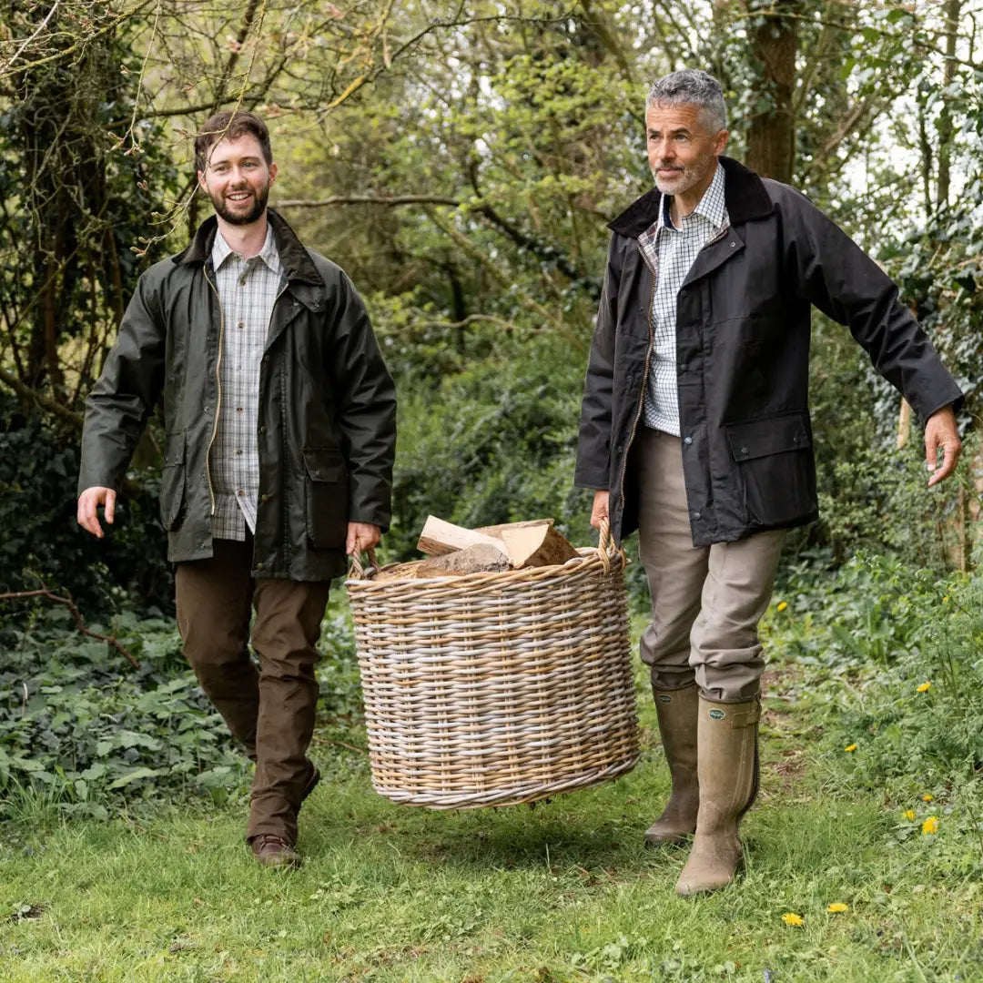 Two men in a wooded area wearing Mens Cupra Wax Jacket while carrying a basket