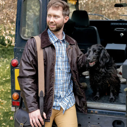 Man in a Mens Classic Antique Wax Jacket with a black dog in a vehicle