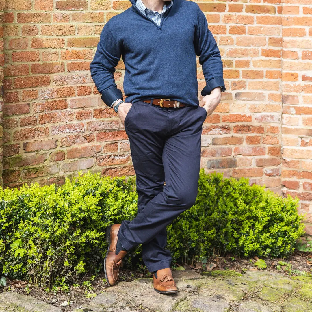 Man in a blue sweater and navy pants showcasing Forest Classic Chinos against a brick wall