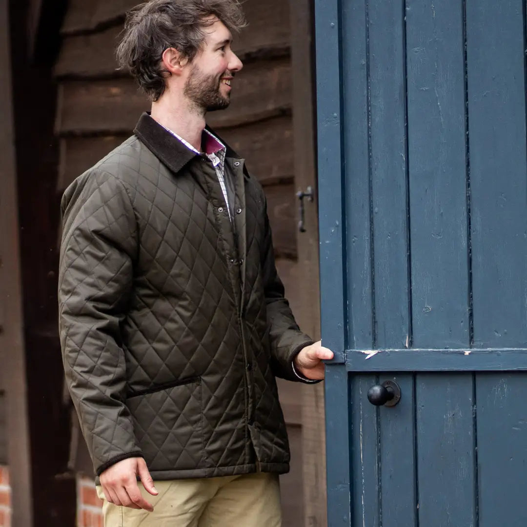 Man in a dark Forest Classic Quilted Jacket opening a blue door