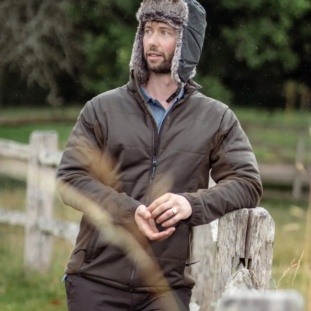 Man in a brown forest padded jacket and fur-lined hat providing added warmth outdoors