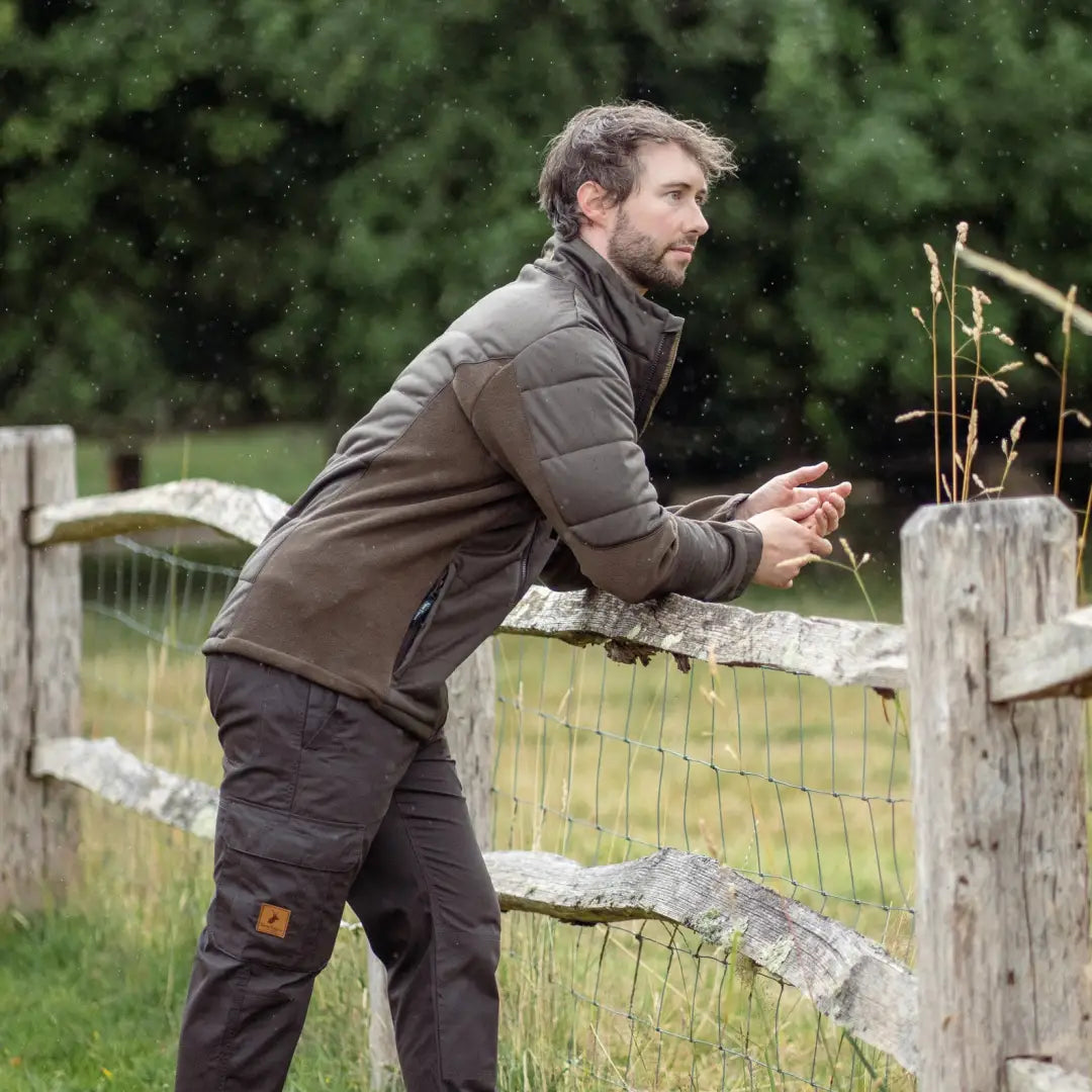 Man in a brown New Forest Falcon Padded Jacket leaning on a wooden fence for added warmth