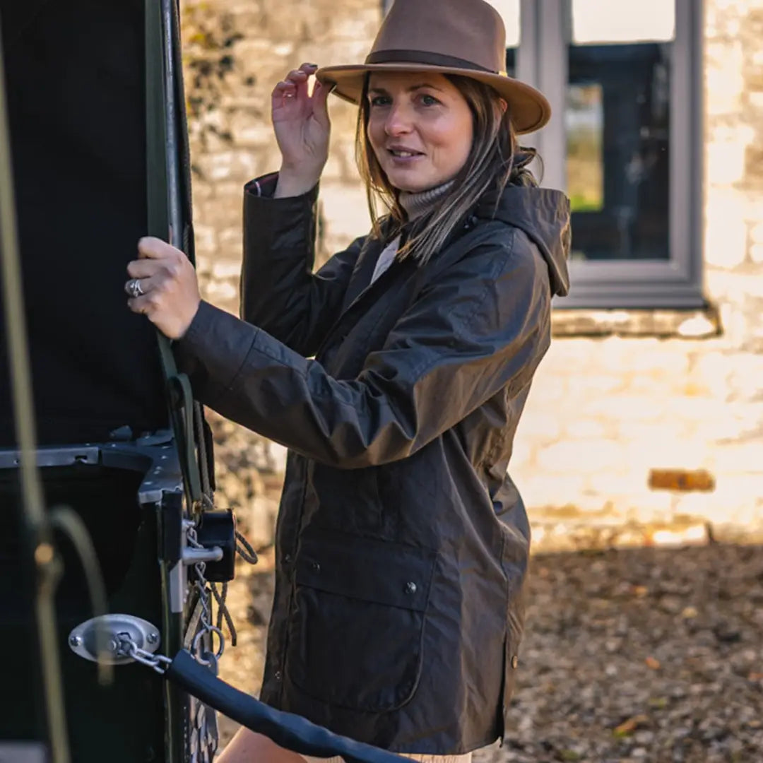 Woman in a brown hat and dark jacket, styling her New Forest Freya Ladies Wax Jacket