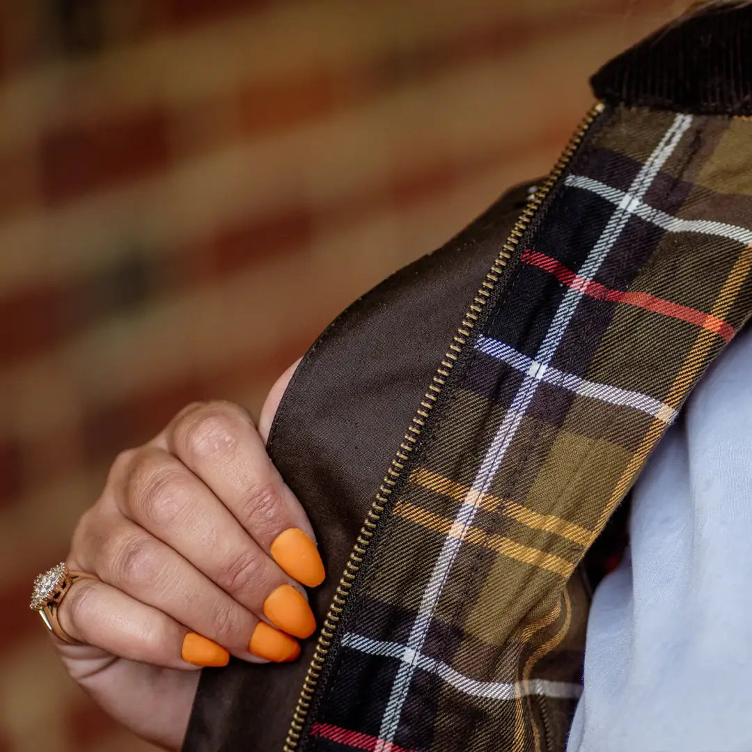 Hand with orange nails and diamond ring, showcasing the Forest Freya Ladies Wax Jacket