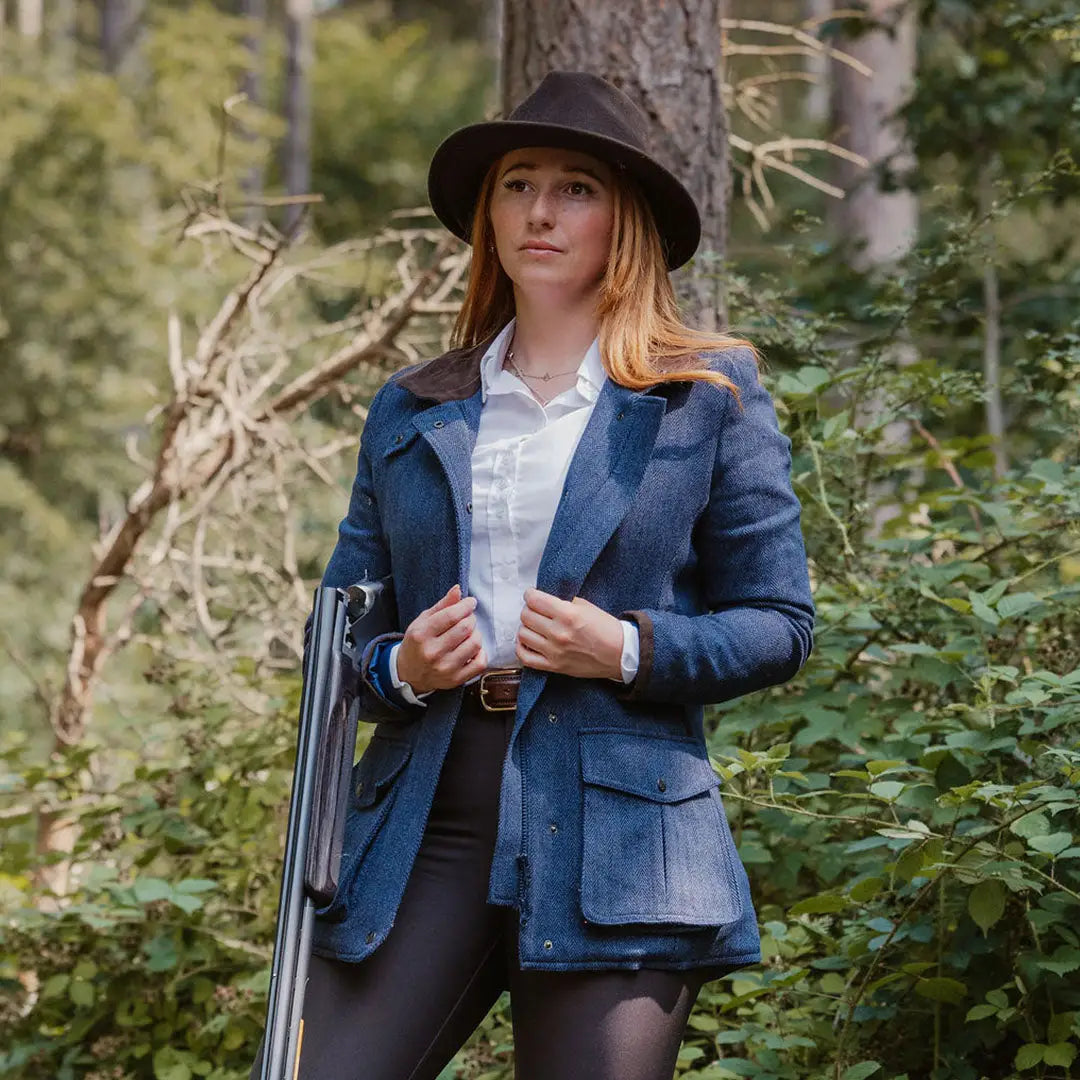 Woman in a blue blazer and black hat with a laptop, showcasing the Forest Jessica Tweed Field Coat