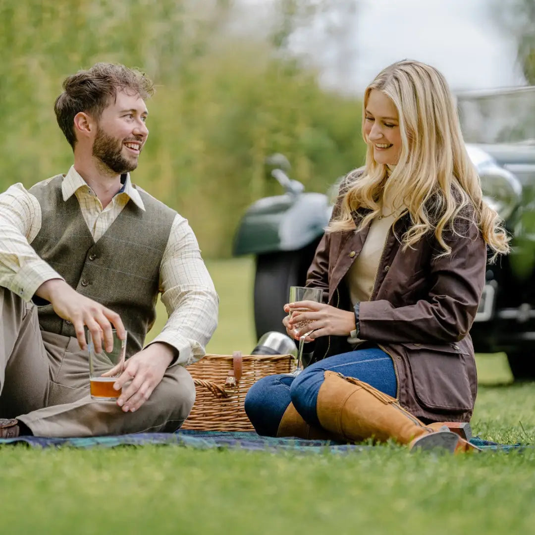 Couple enjoying a picnic on grass while wearing an Antique Wax Jacket