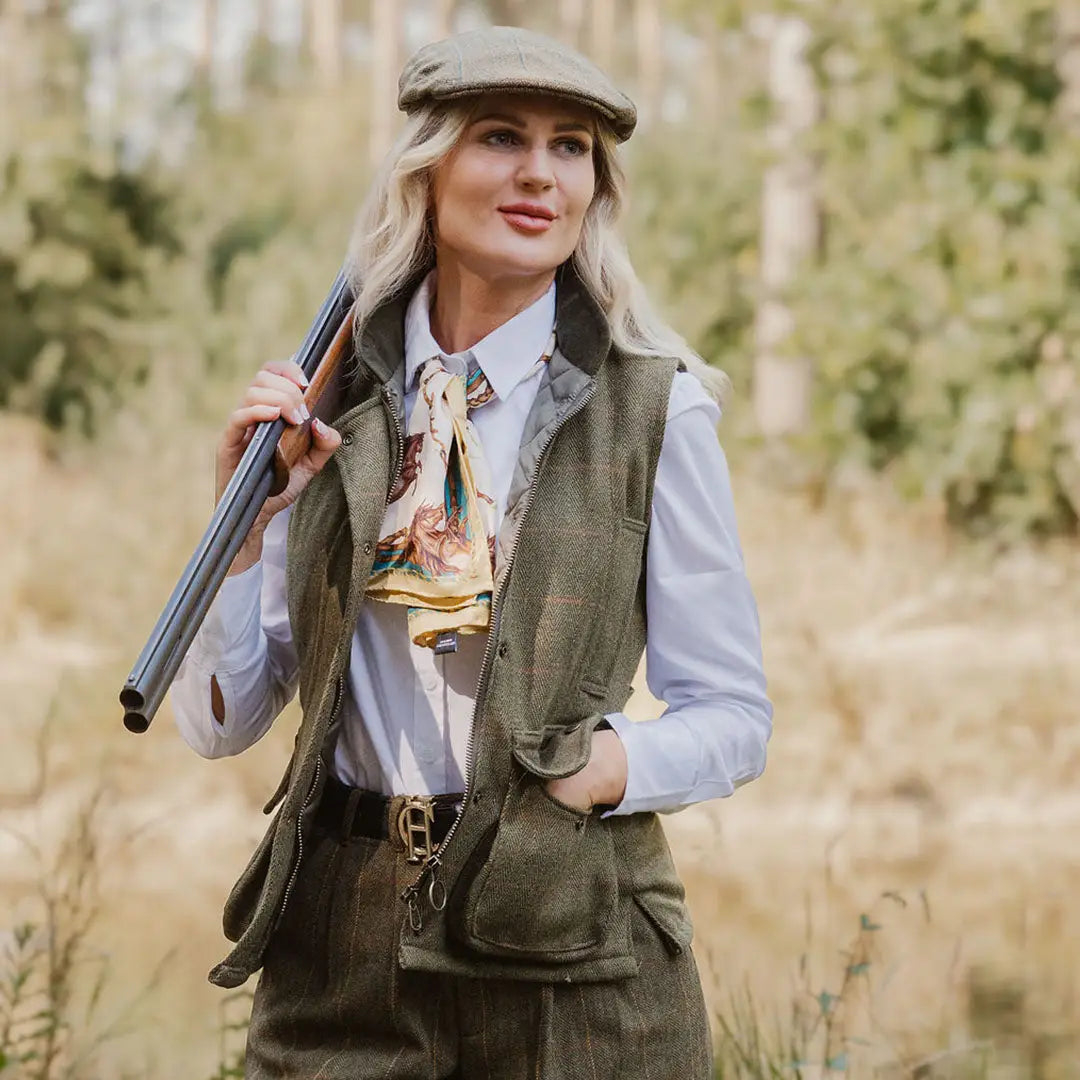 Woman in hunting gear with a shotgun showcasing the New Forest Ladies Tweed Gilet