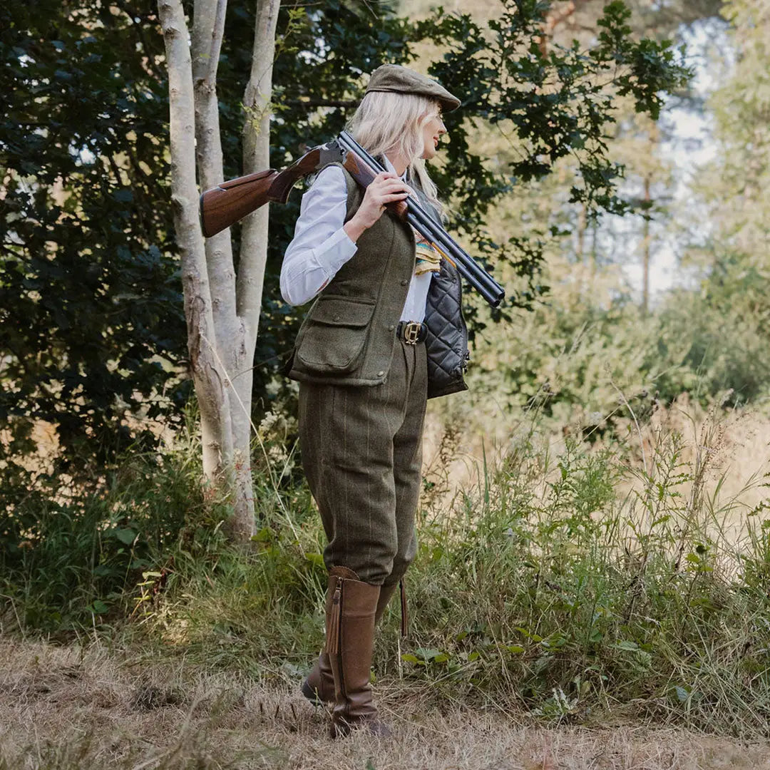 Hunter in a stylish New Forest Ladies Tweed Gilet with a shotgun in hand