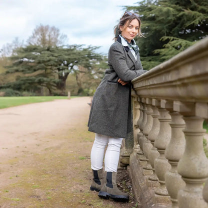 Woman in a gray Forest Lizzie Tweed Coat leaning on a stone balustrade