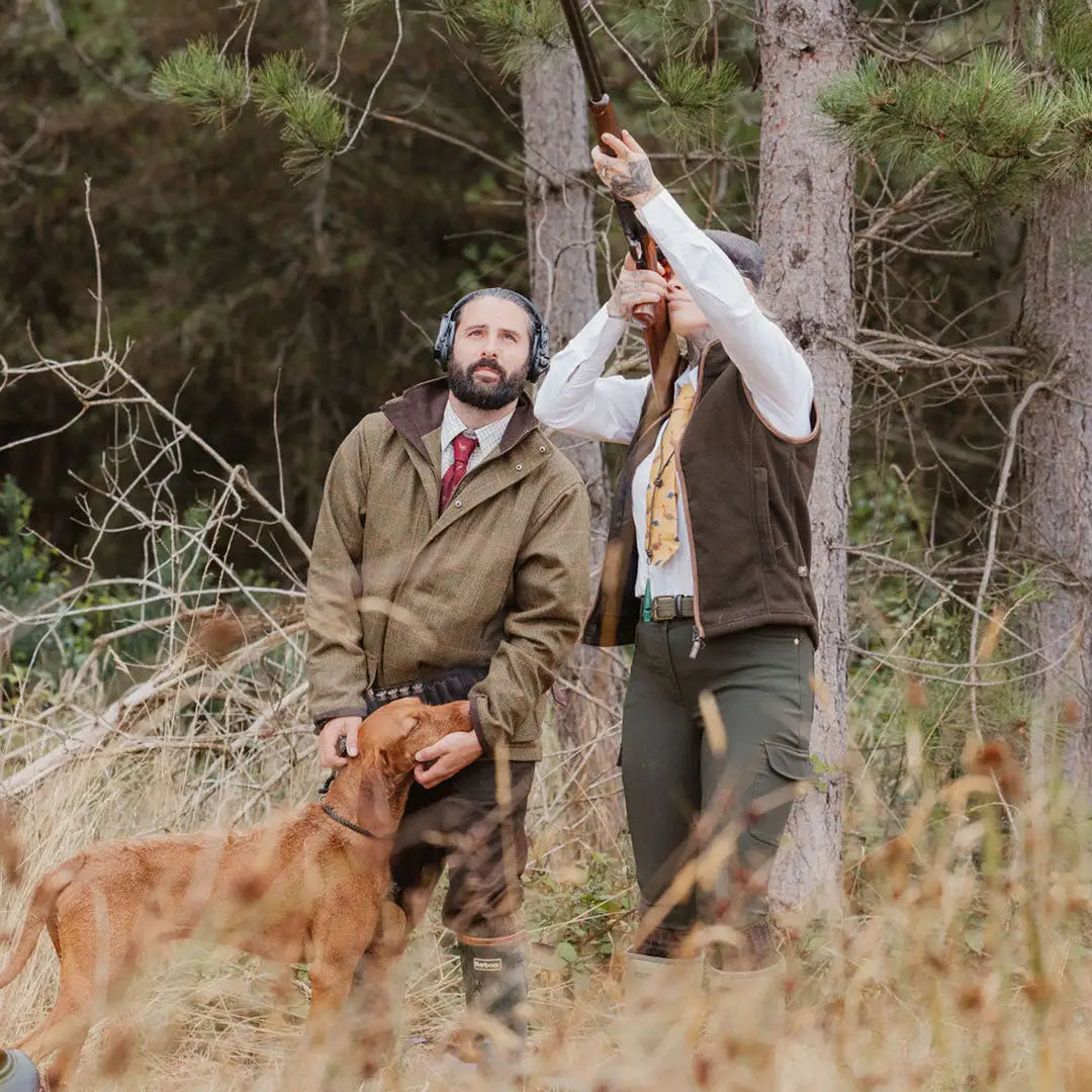 Two men and a dog in the woods wearing the New Forest Maverick Waterproof Tweed Jacket