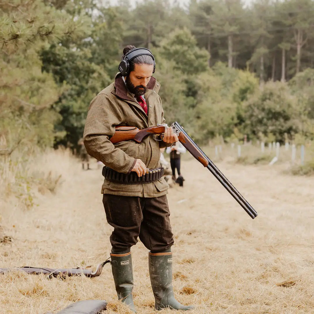 Hunter with a shotgun in a New Forest Maverick Waterproof Tweed Jacket outdoors