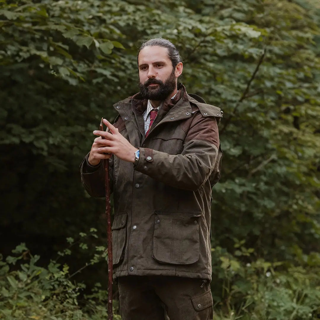 Bearded man in brown waxed jacket and red tie showcasing Forest Performance Field Coat