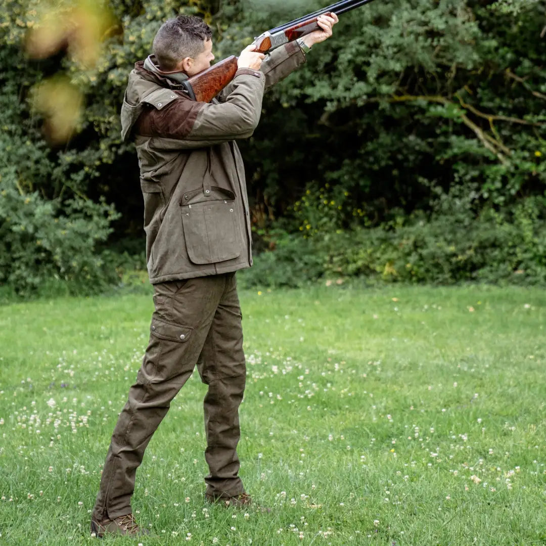 Man in hunting gear aiming shotgun, showcasing New Forest Performance Field Trousers