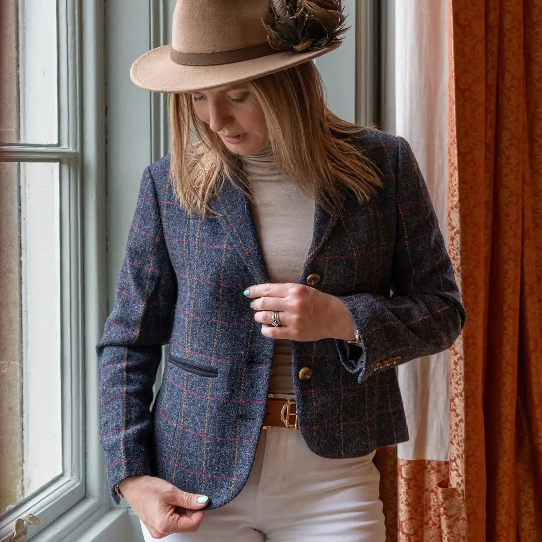 Woman in a forest Polly tweed blazer and fedora hat by a window