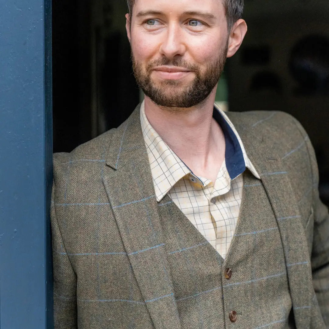 Man with dark hair in a wool tweed blazer over a plaid shirt showcasing style