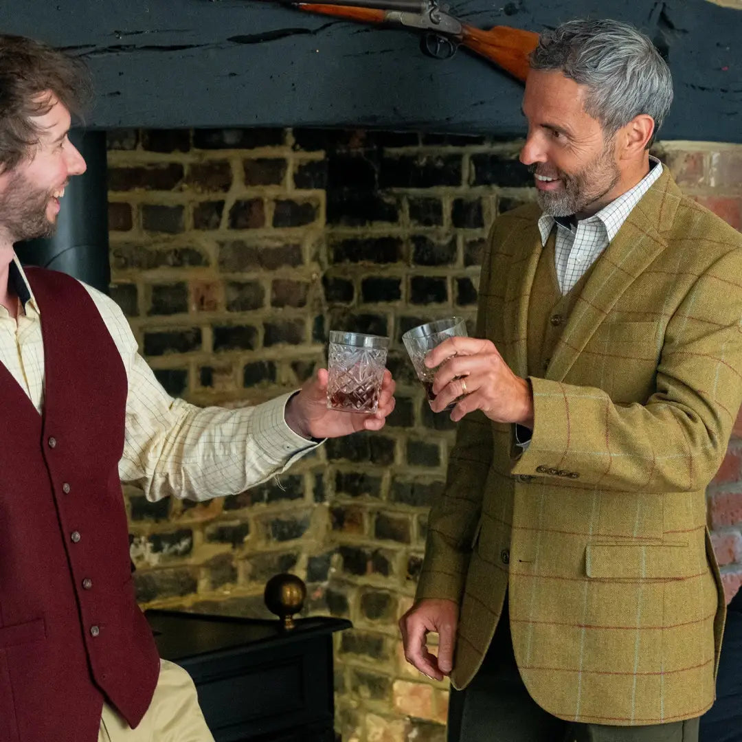 Two men toasting with whiskey while wearing a stylish wool tweed waistcoat