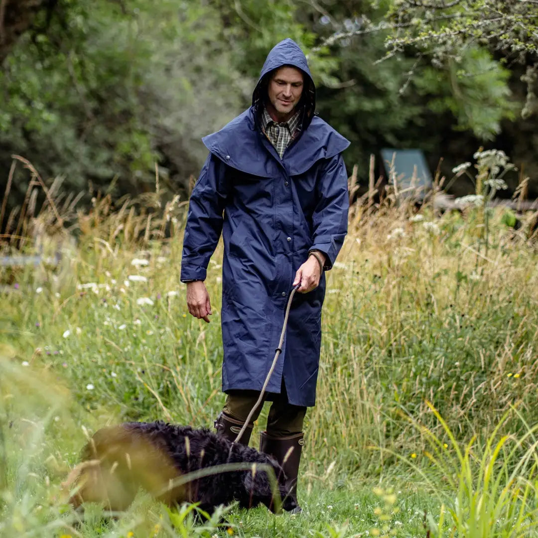 Person in a blue raincoat walking a dog in tall grass, perfect for country clothing and outdoors