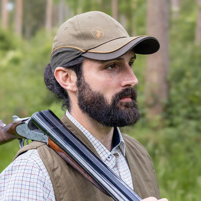 Bearded man with a shotgun rocking the New Forest Skeet Cap outdoors