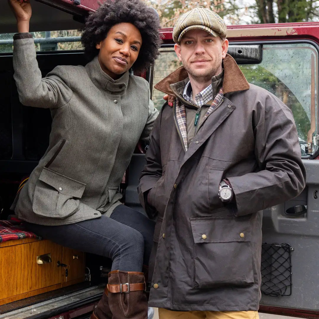 Vintage red Land Rover with two people enjoying the outdoors in their traditional wax jacket