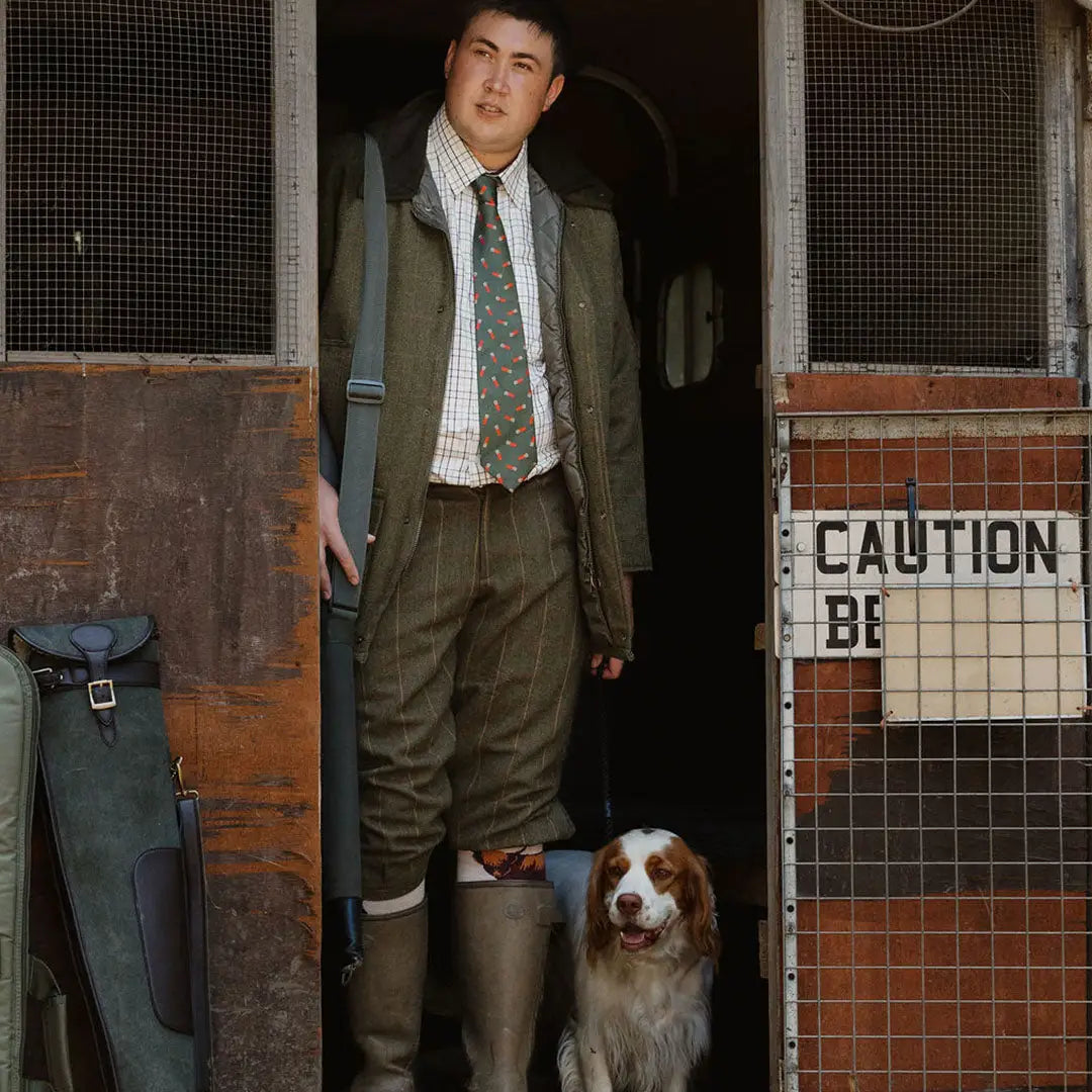 Man in a green suit with his Spaniel dog showcasing a stylish English made tweed shooting jacket