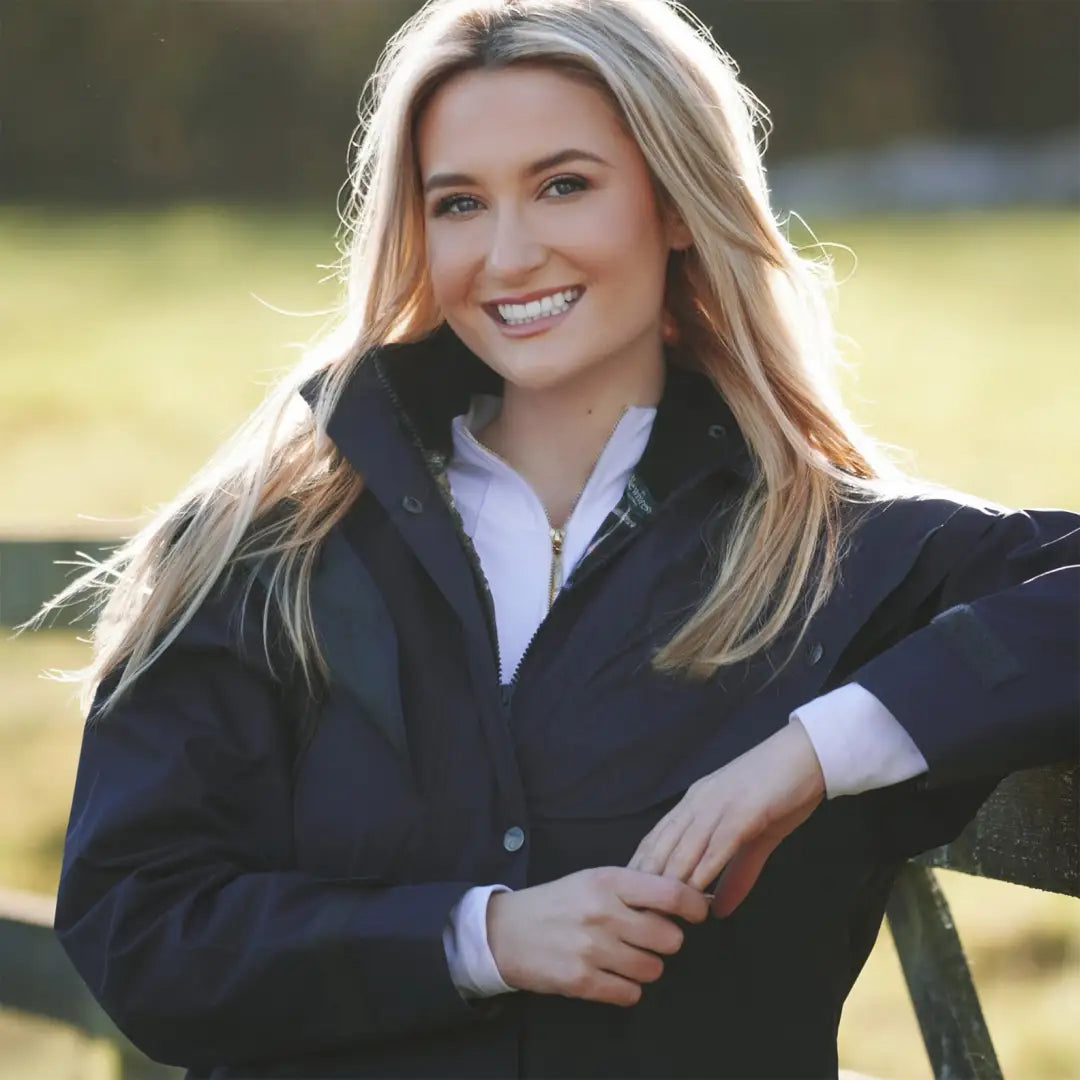 Smiling blonde woman in black jacket showcasing New Forest Victoria waterproof coat