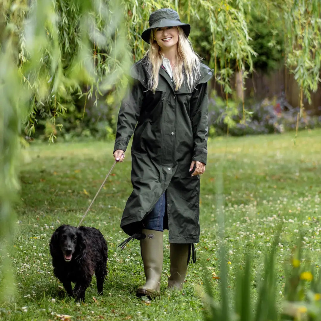 Person in a green Victoria Cape walking a black dog in ultimate wet weather gear