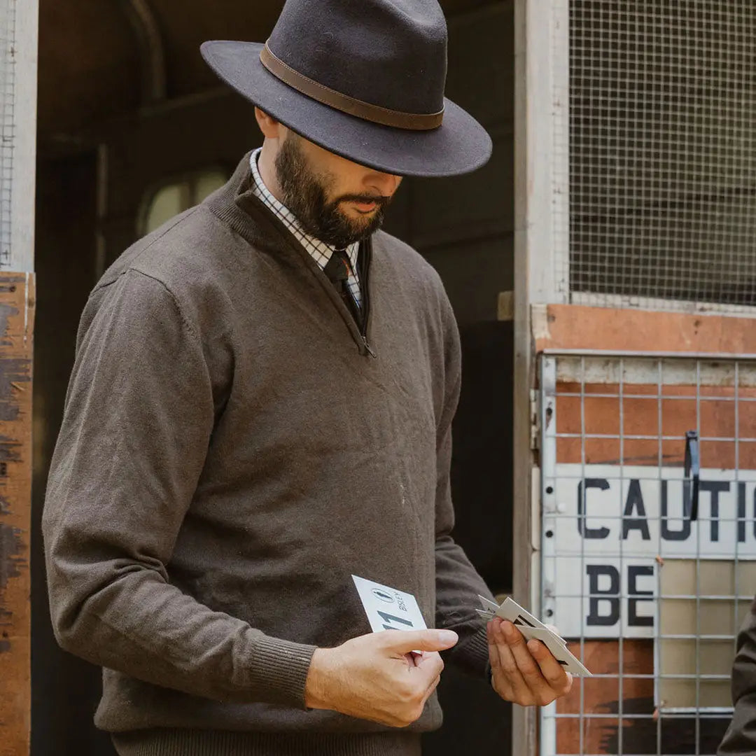 Man in gray fedora and sweater admiring his New Forest zip neck jumper