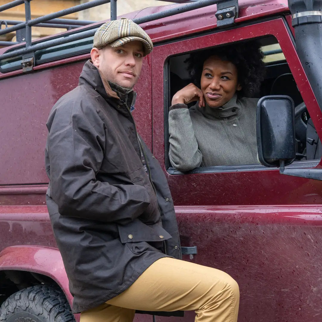 Red off-road vehicle with two people wearing padded wax jackets enjoying the outdoors