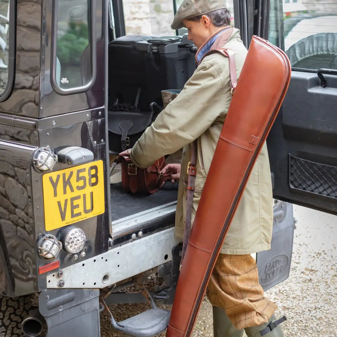 Person in countryside attire getting into a Land Rover with Parker-Hale Leather Shotgun Slip