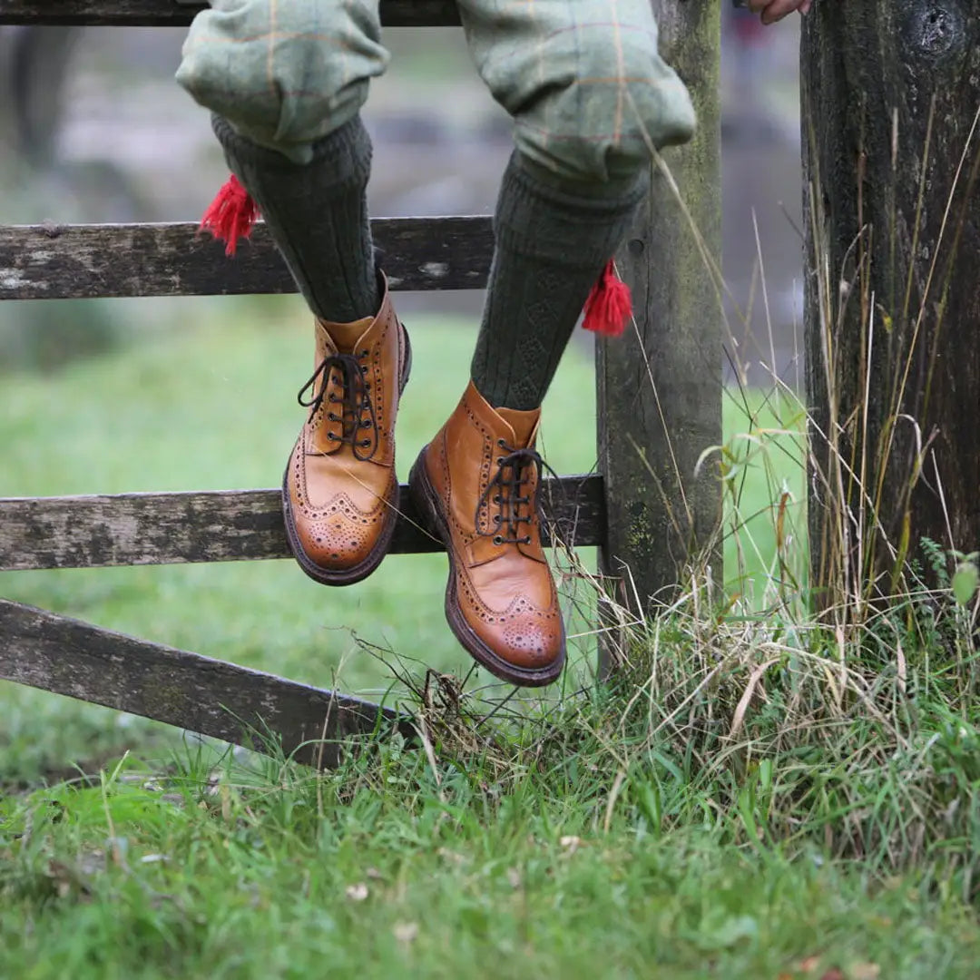 Brown leather wingtip boots with green pants and red Pennine Beater Socks in premium wool