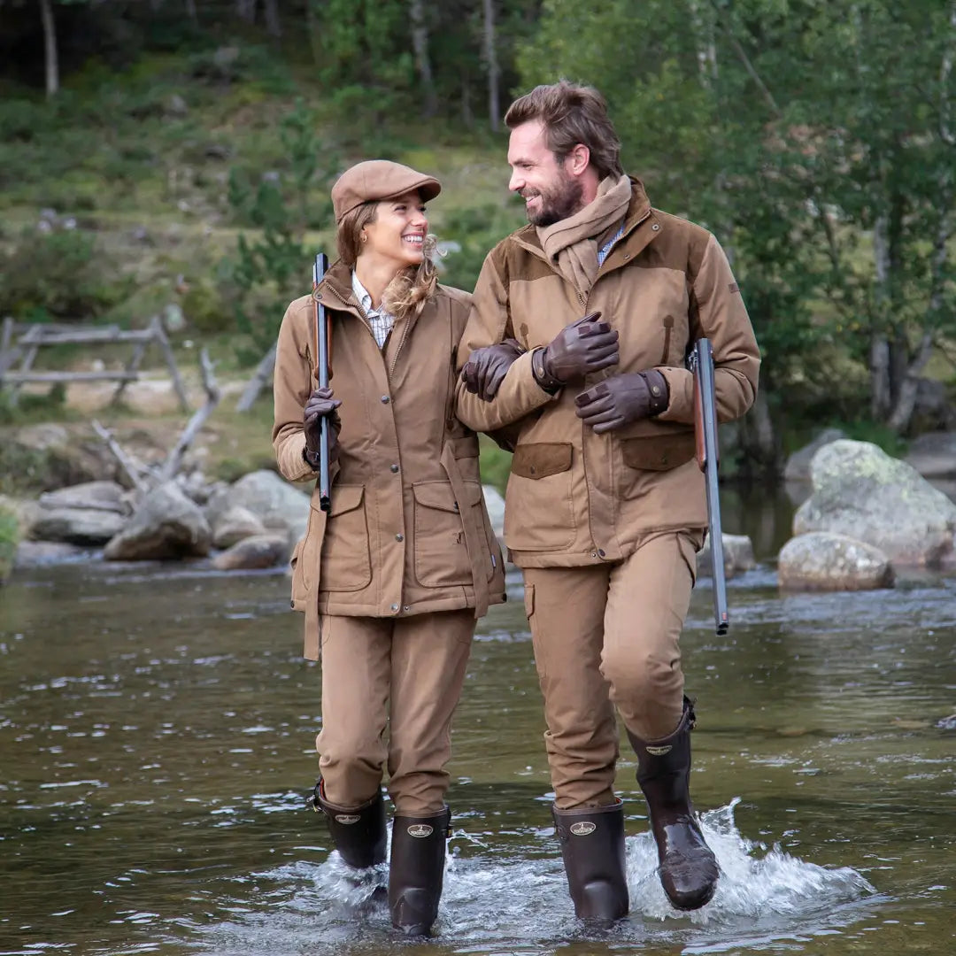 Couple in outdoor gear walking through a stream wearing Rambouillet Hunting Jacket