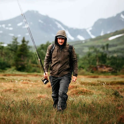 Fisherman in a grassy field with a fishing rod wearing a stretchy lightweight 3-layer jacket