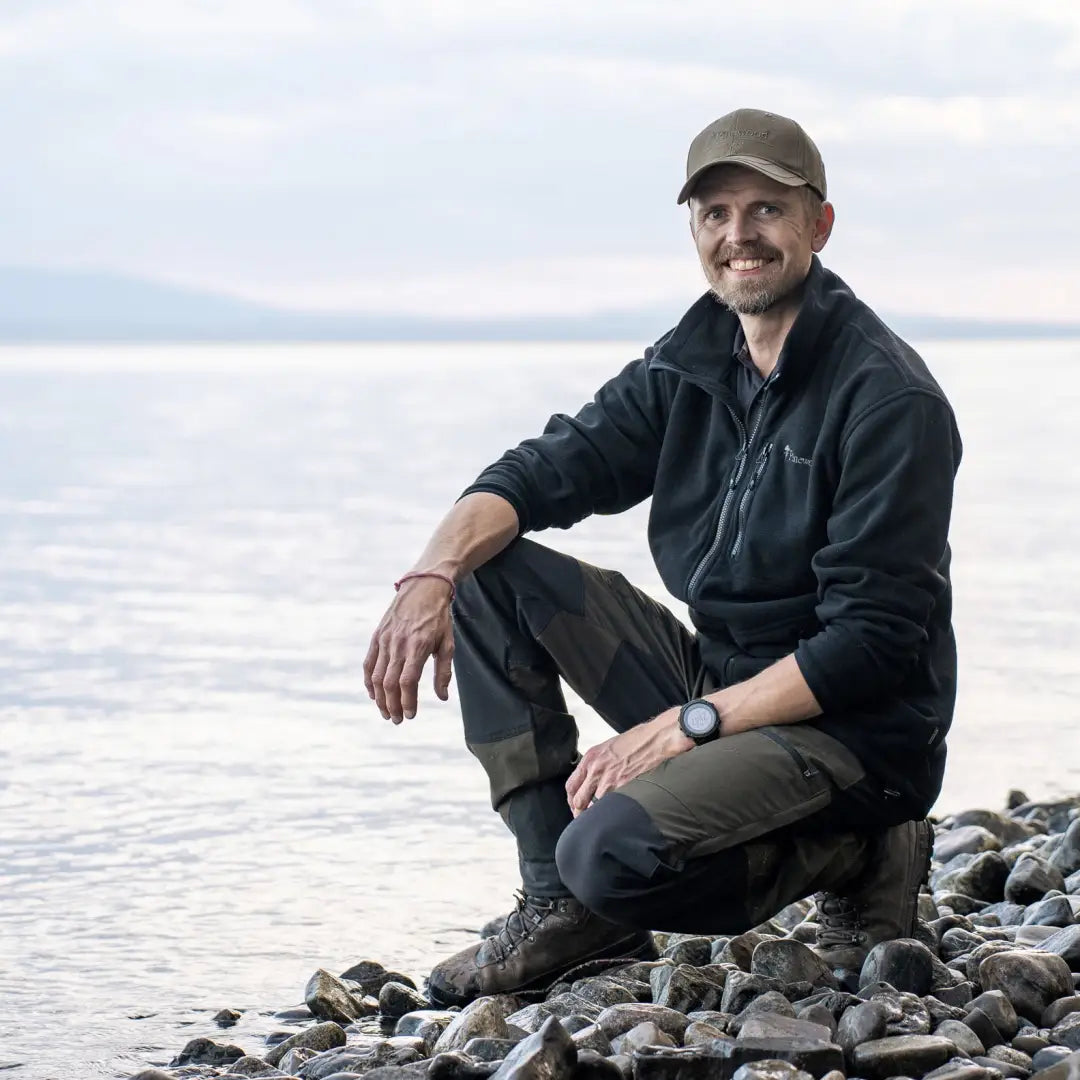 Man in casual outdoor wear on rocky shore, featuring Pinewood Caribou TC Men’s Trousers