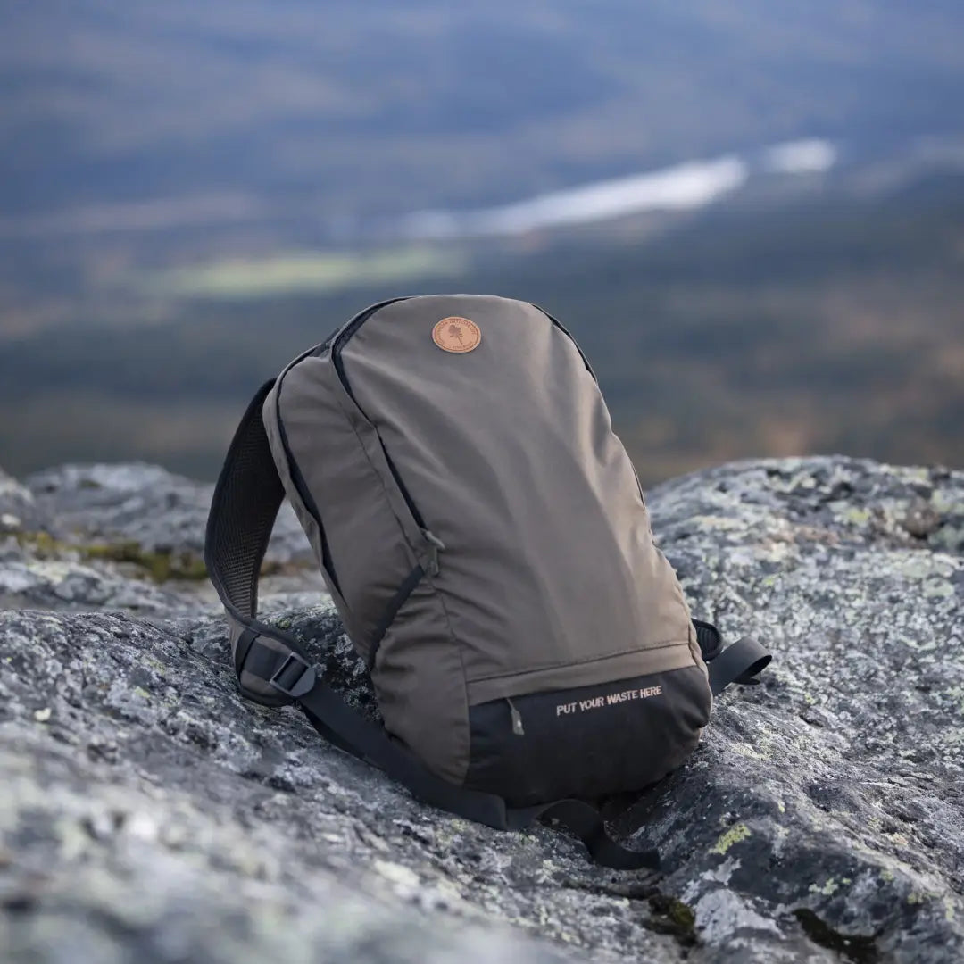 Gray Pinewood Day Pack 22L resting on rocky terrain, perfect for outdoor adventures