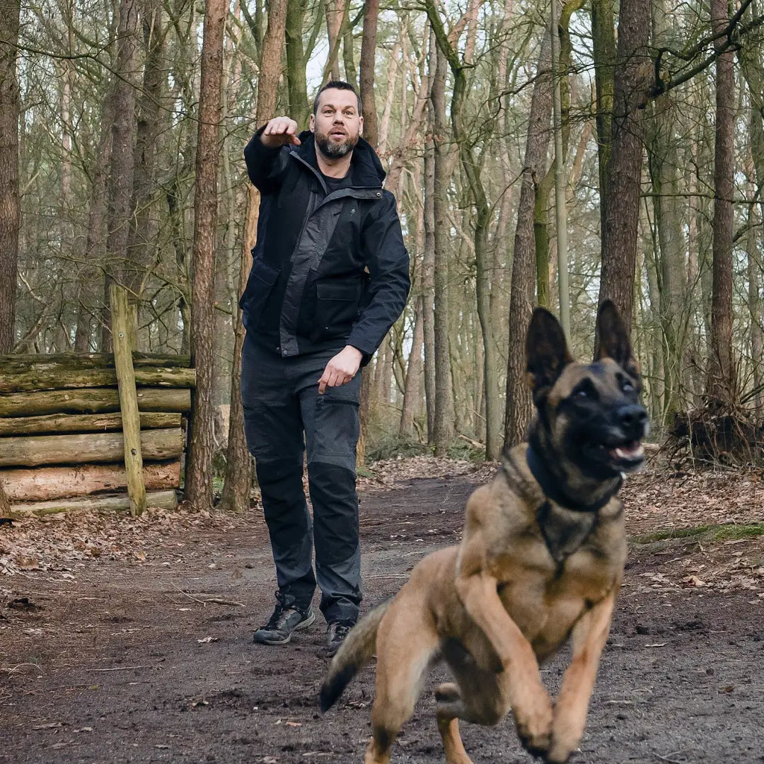 Man walking a German Shepherd in the forest wearing a Pinewood Dog Sports 2.0 Jacket