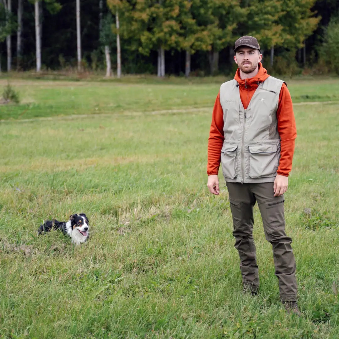 Man in Pinewood Dog Sports Vest 2.0 enjoying a grassy field with a small dog