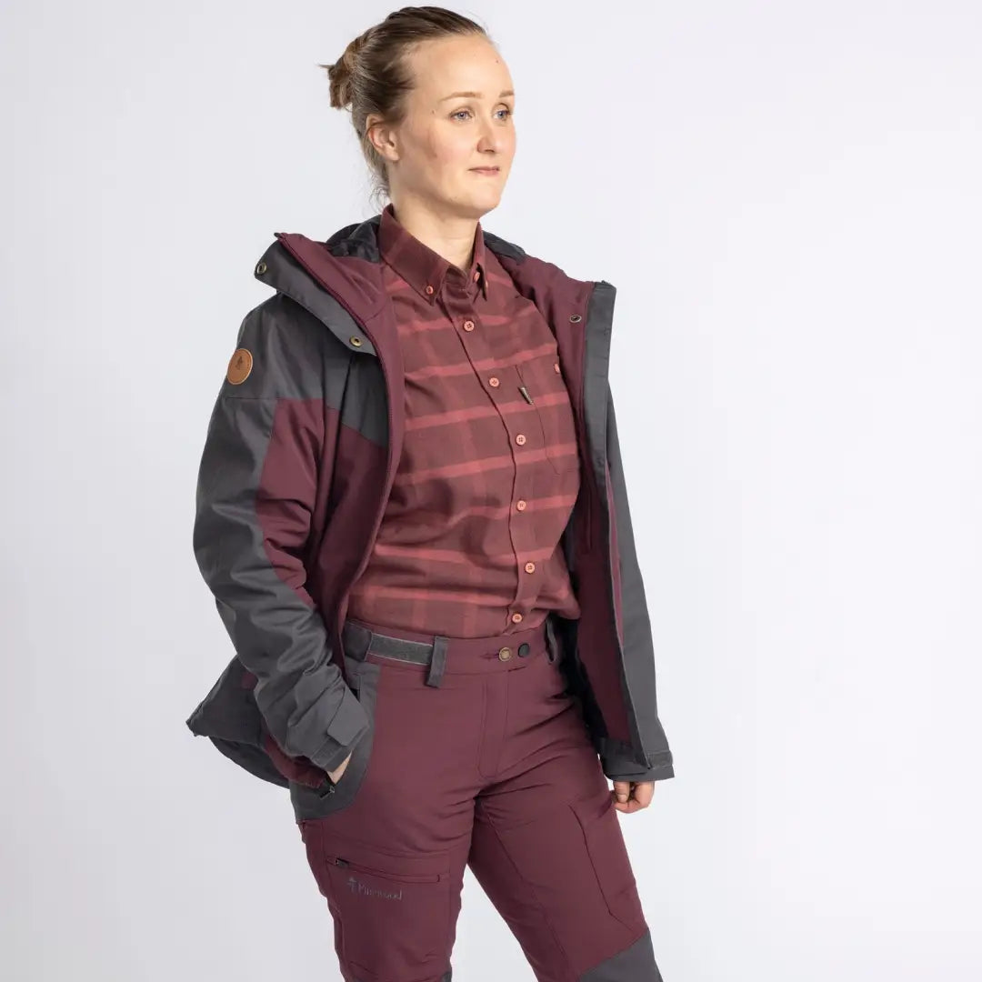 Woman in a burgundy outfit sporting the Pinewood Ladies Finnveden Hybrid Extreme Jacket for outdoors