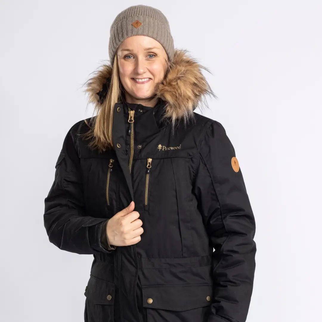 Black Finnveden Winter Parka with fur-trimmed hood and beige knit hat for cozy style