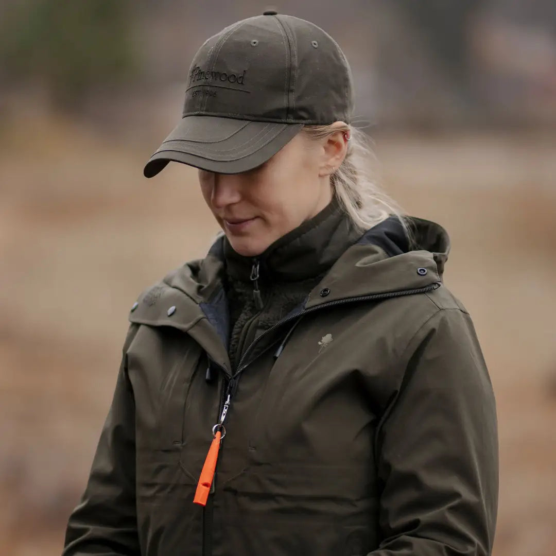 Person in a dark green 3-layer jacket with adjustable hood, styling country clothing