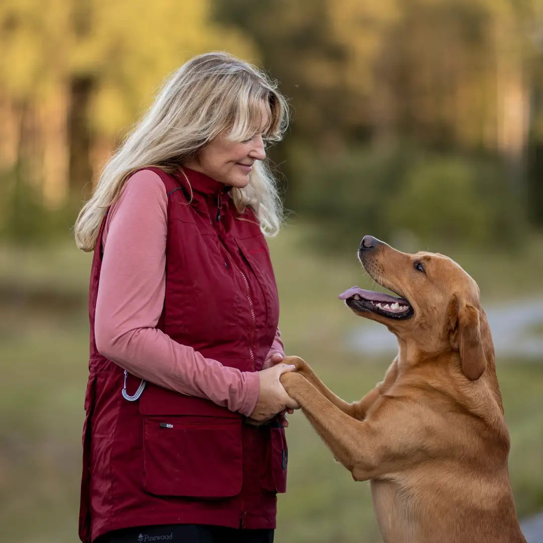 Woman wearing a training vest cuddles her golden retriever with love