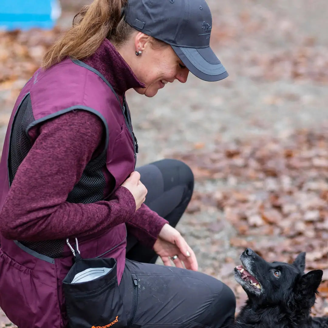 Woman enjoying the outdoors in a Pinewood fleece jacket while petting a small black dog