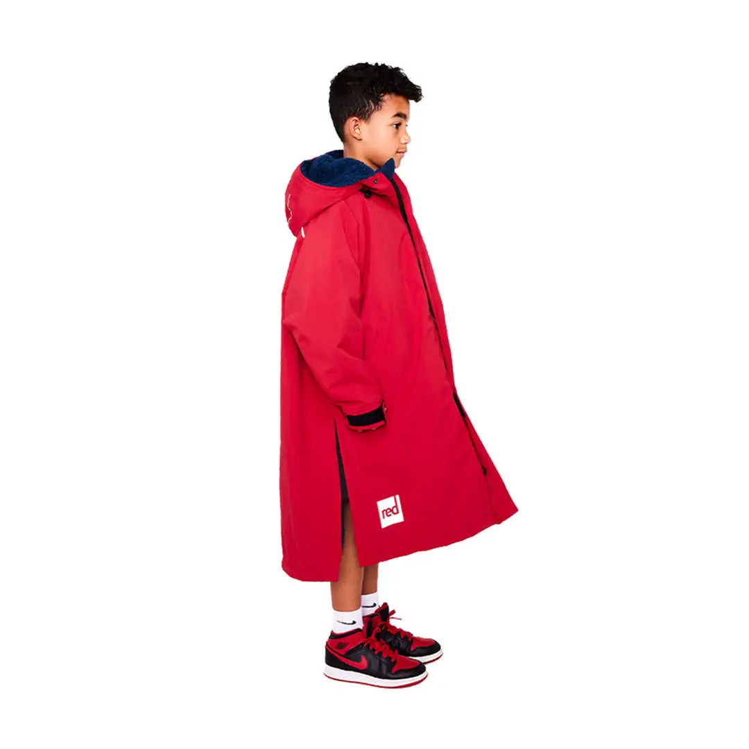 Bright red kids pro robe with navy collar and hood worn by a happy child