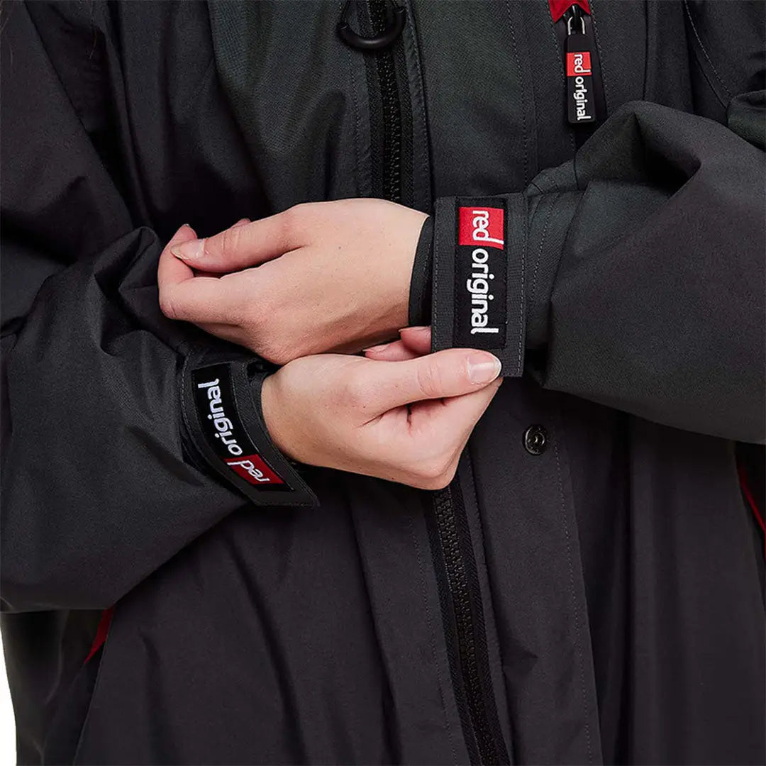 Hands adjusting the cuff of a black jacket with red Original logo for the Evo Changing Robe