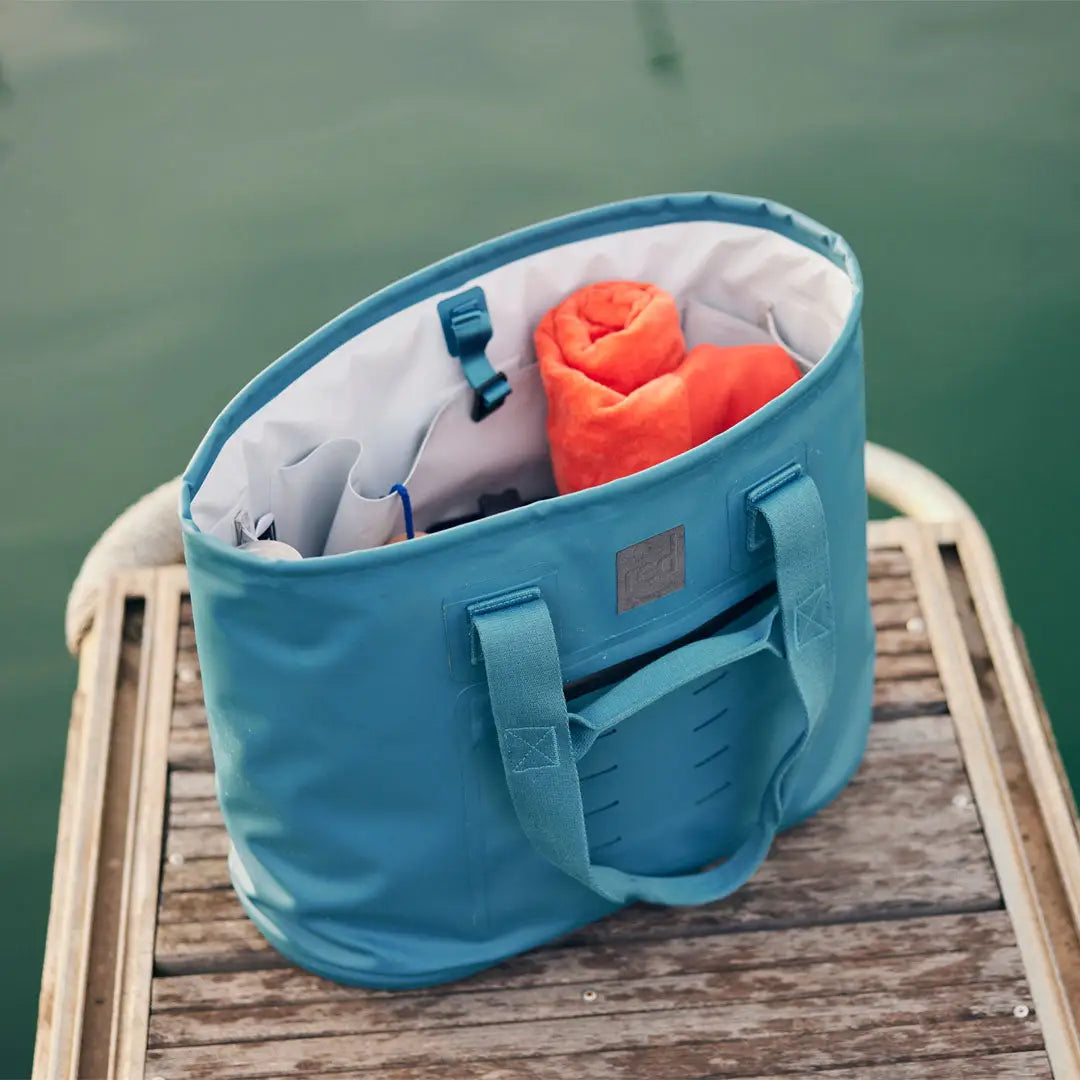 Teal waterproof tote bag with orange item and country clothing for hunting adventures