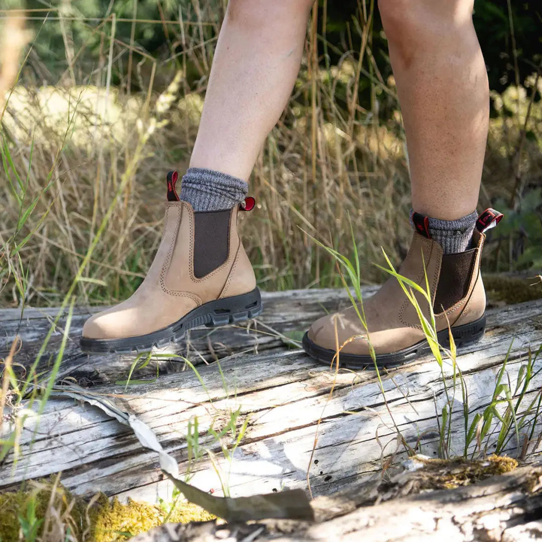 Beige Redback Bobcat Soft Toe Boots with cozy gray cuffs on weathered wood