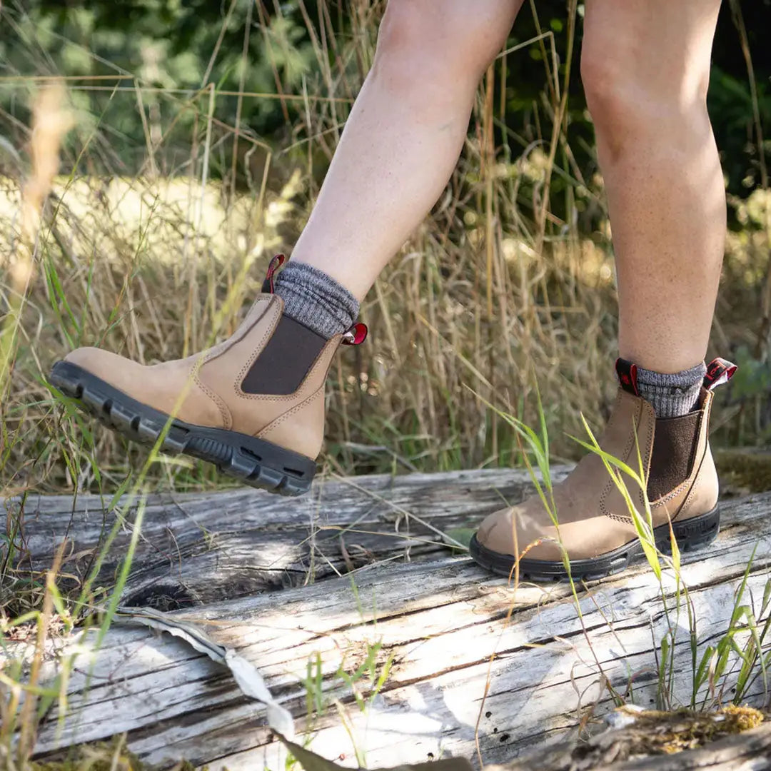 Beige and brown Bobcat Soft Toe Boots with knitted cuffs on weathered wood