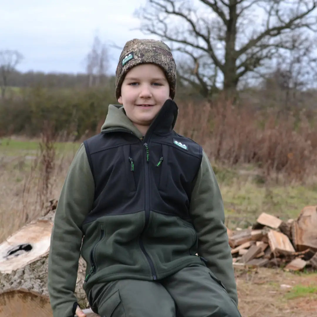 Young person in a camouflage hat wearing Ridgeline Kids Hybrid Fleece Gilet outdoors